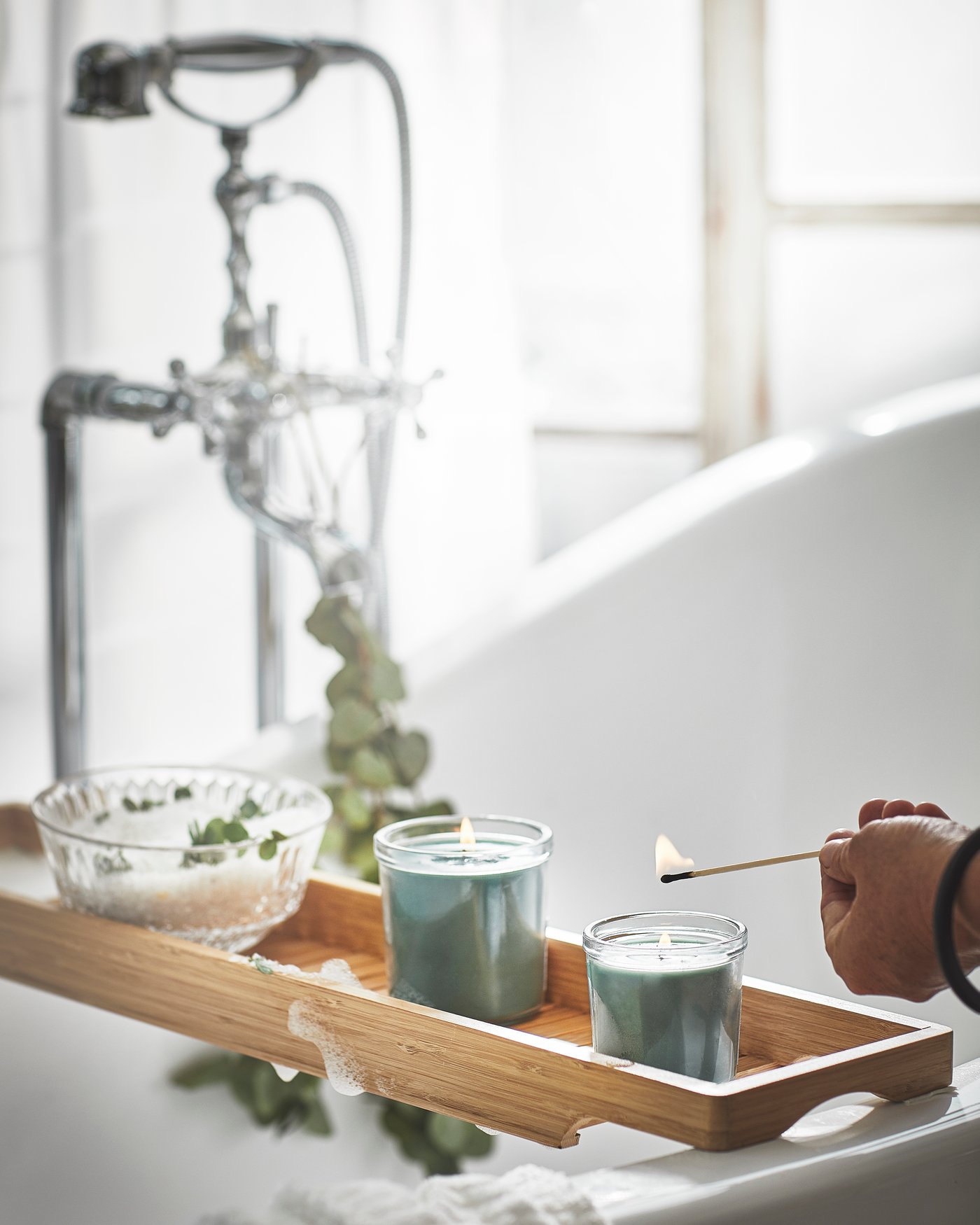 Un gros plan sur un disque en bois d'arbre dans un ton brun doré sur lequel se trouve une bougie parfumée avec de la cire de bougie blanche dans un récipient en pierre noire marbrée.