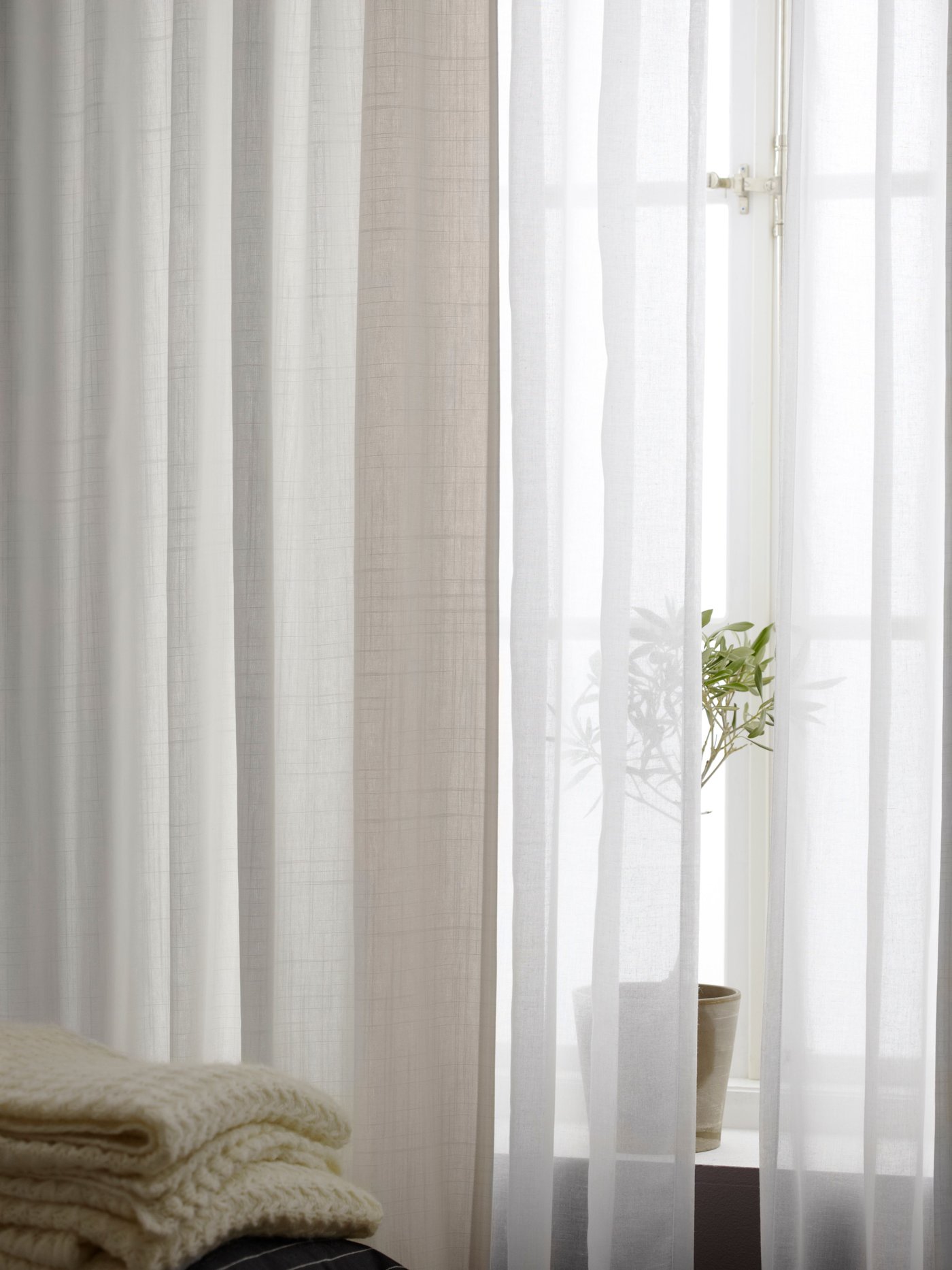 White SILVERLÖNN sheer curtains and beige sheer curtains in front of a living‑room window.