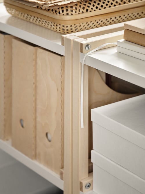 A section of the EKENABBEN shelving unit holding boxes and baskets, showing the join between the frame and the shelves.