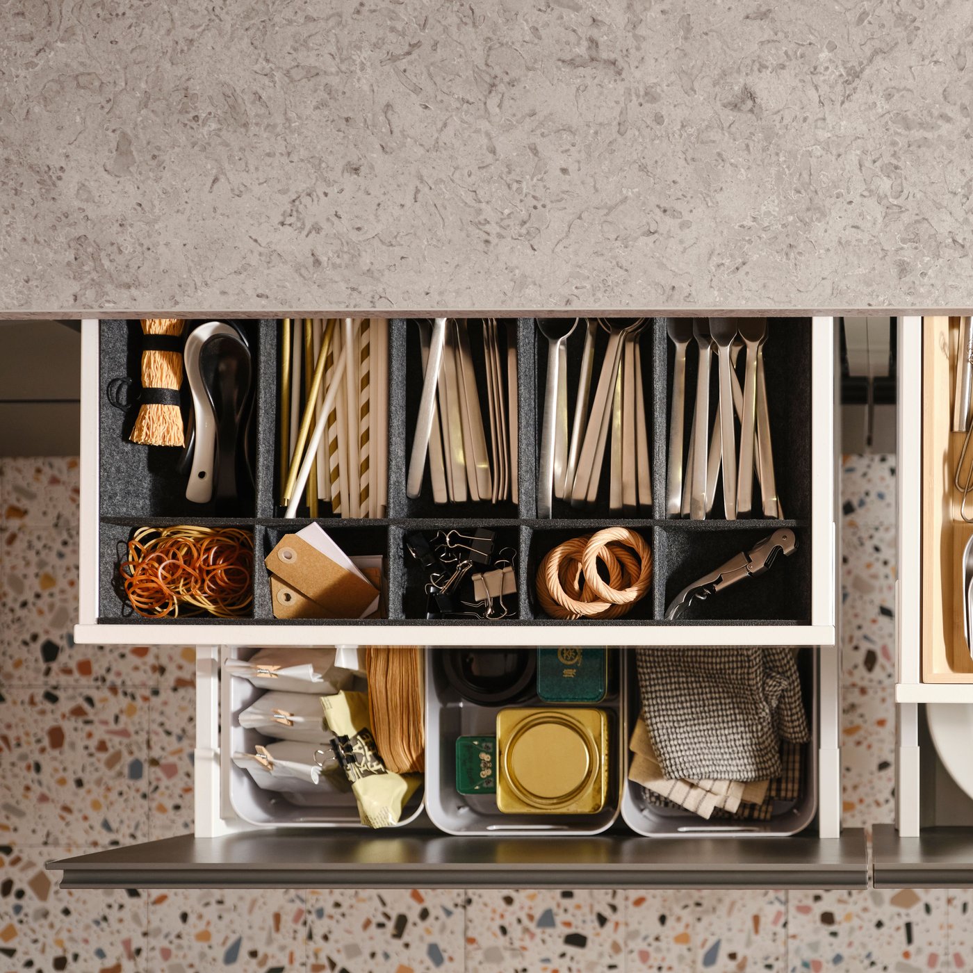 Es sind vier ausgezogene MAXIMERA Küchenschubladen mit verschiedenen Gegenständen in einem Besteckkasten, einem verstellbaren Einsatz und Boxen zu sehen.