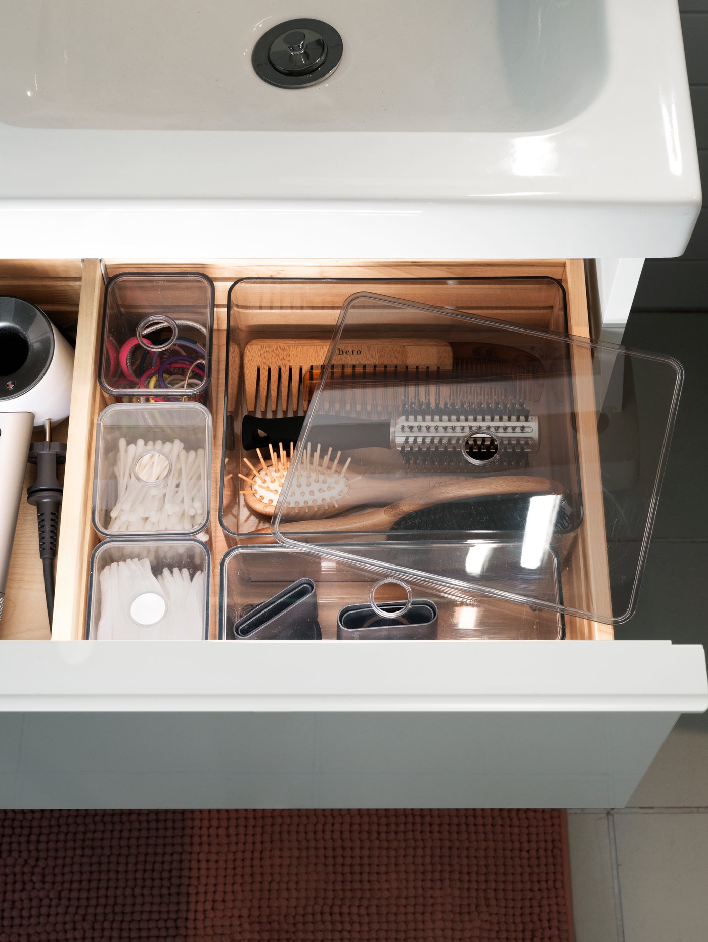 Odprt predal s prozornimi organizatorji, v katerih so krtače in potrebščine.