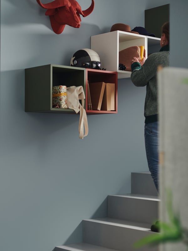 EKET cabinets, in different colours, are mounted on a blue wall, next to a decorative red buffalo head.