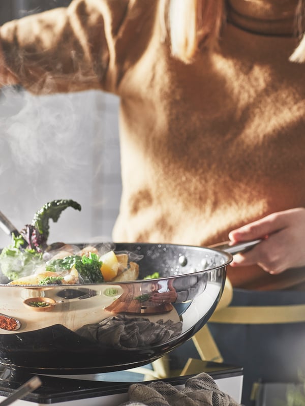 Iemand gooit het eten in een wok omhoog om het om te roeren.