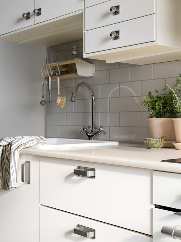 A METOD kitchen with white VEDDINGE fronts, SÖRBYN handles and knobs and a beige marble effect/quartz KASKER worktop.