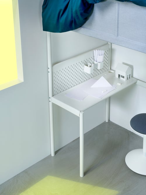 Bureau VITVAL blanc, sous un lit mezzanine avec différents accessoires pour enfants et un petit tabouret à côté du bureau.