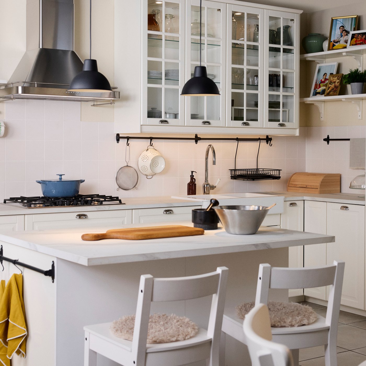 A kitchen with BODBYN drawer fronts and doors in off-white, HEKTAR pendant lamps and traditional appliances.