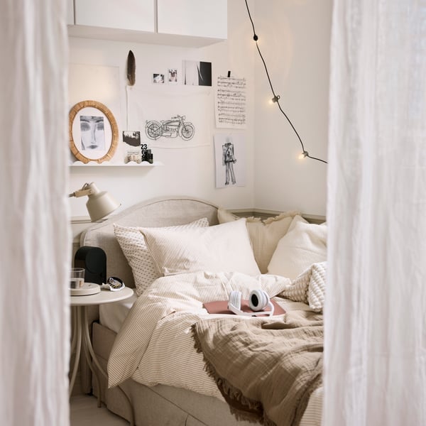 A bedroom scene with a white beige SOLFIBBLA duvet cover and pillowcase set neatly on a bed with striped neutral bedding.