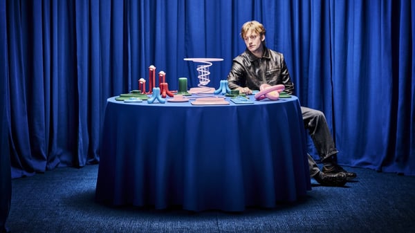homme assis autour d'une table aux tons bleus avec des objets de la collection dessus