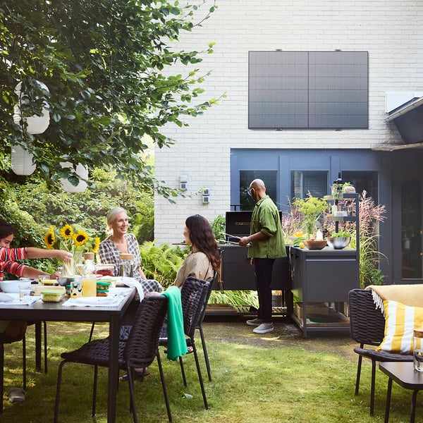 Ein Garten mit Tischen und Stühlen, indem Personen stehen und sitzen.
