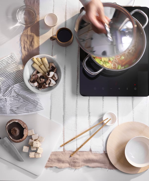 A top view of a person cooking featuring a LEGITIM chopping board and TREBENT chopsticks.