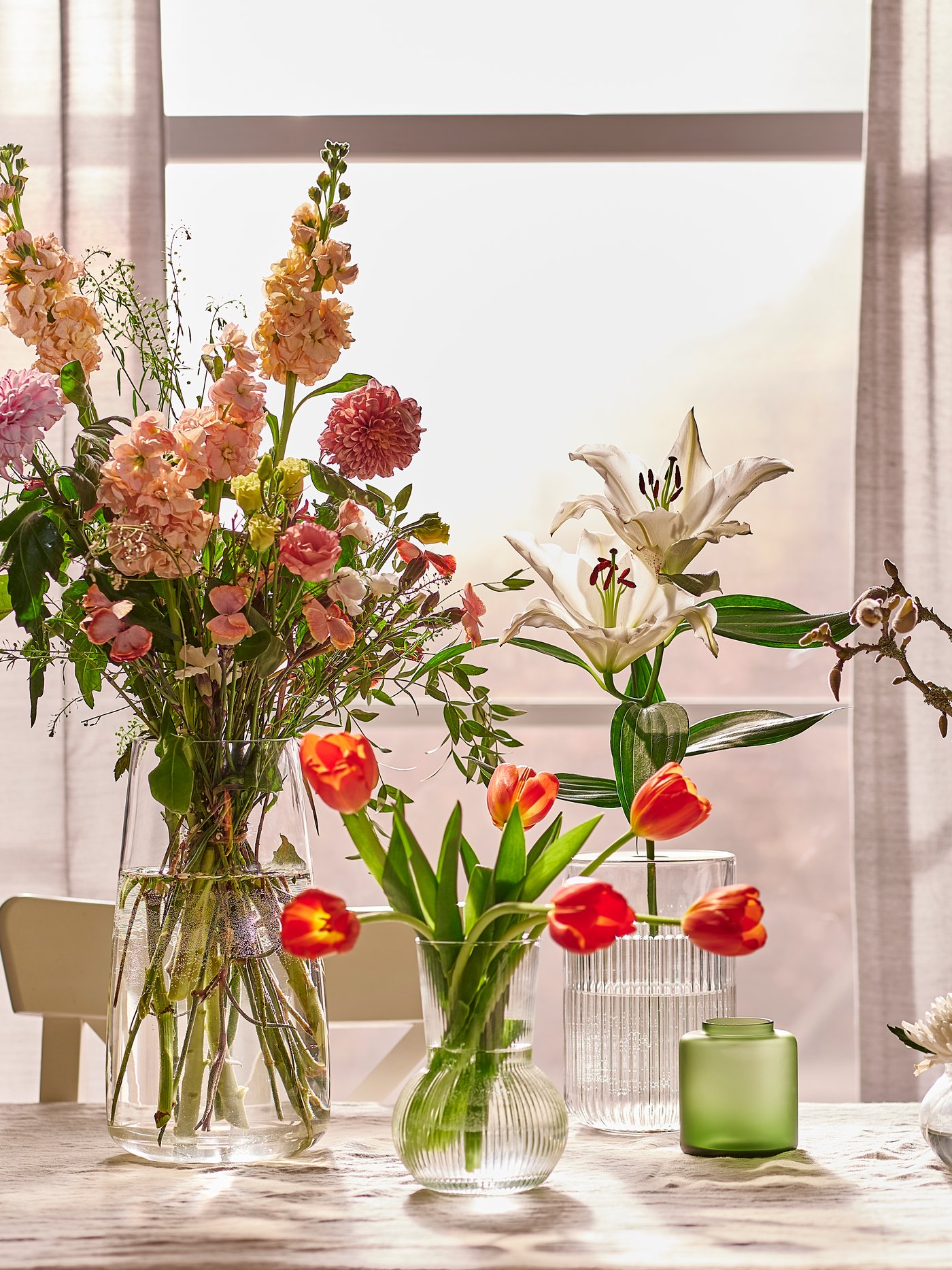 Auf einem Tisch stehen mehrere Vasen mit Blumen gefüllt.