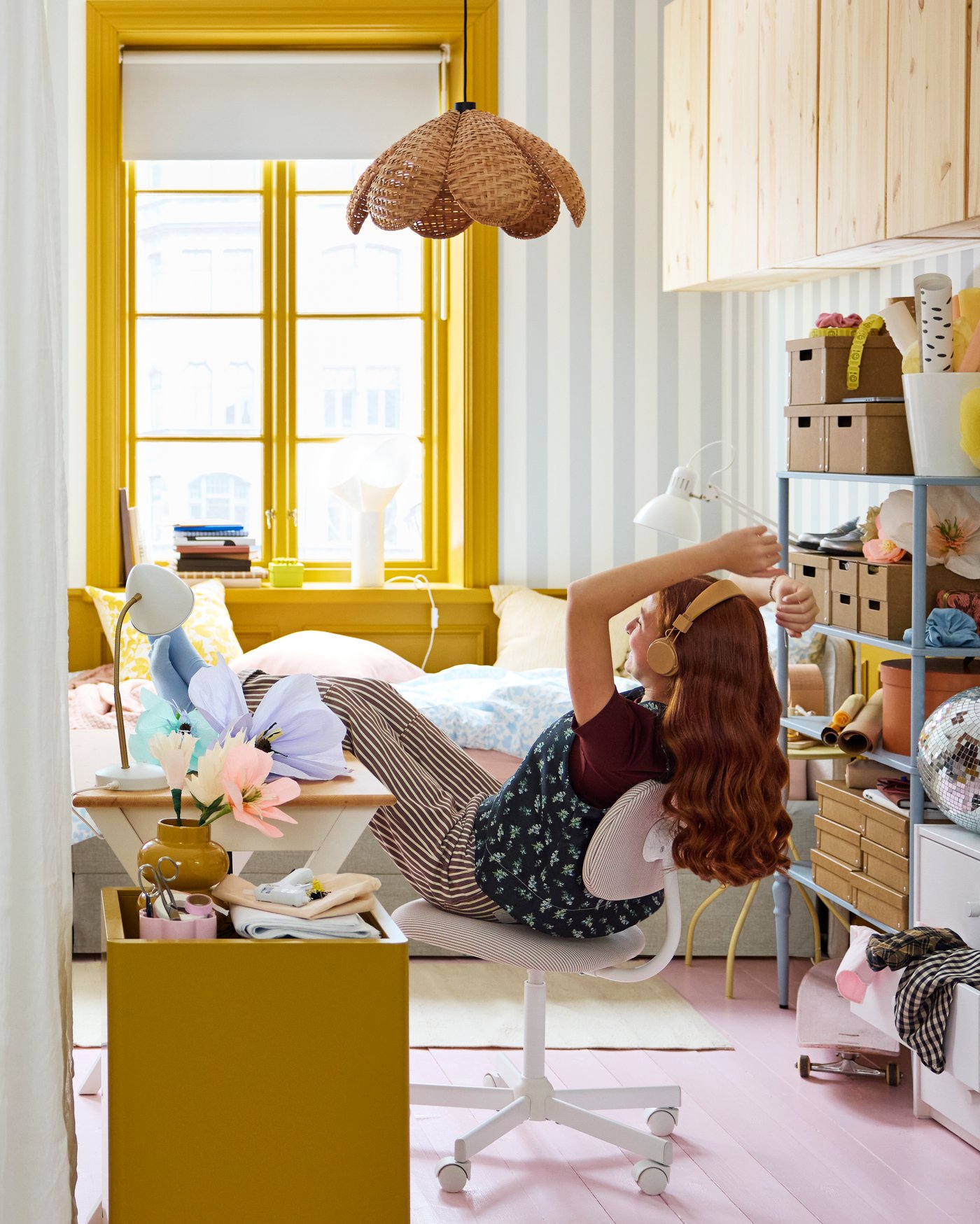 Ett färgstarkt sovrum med en person som ligger avslappnat i en stol, omgiven av skrivbord, förvaring och dekor i varma gula toner.