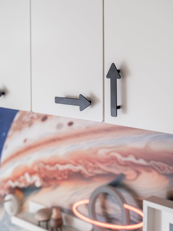 Dettaglio di una maniglia JÄRNSPARV  a forma di freccia posta su un'anta di un pensile SMÅSTAD.