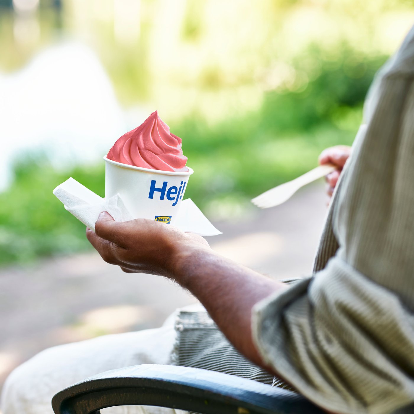 A person holding a cup of soft strawberry ice cream.