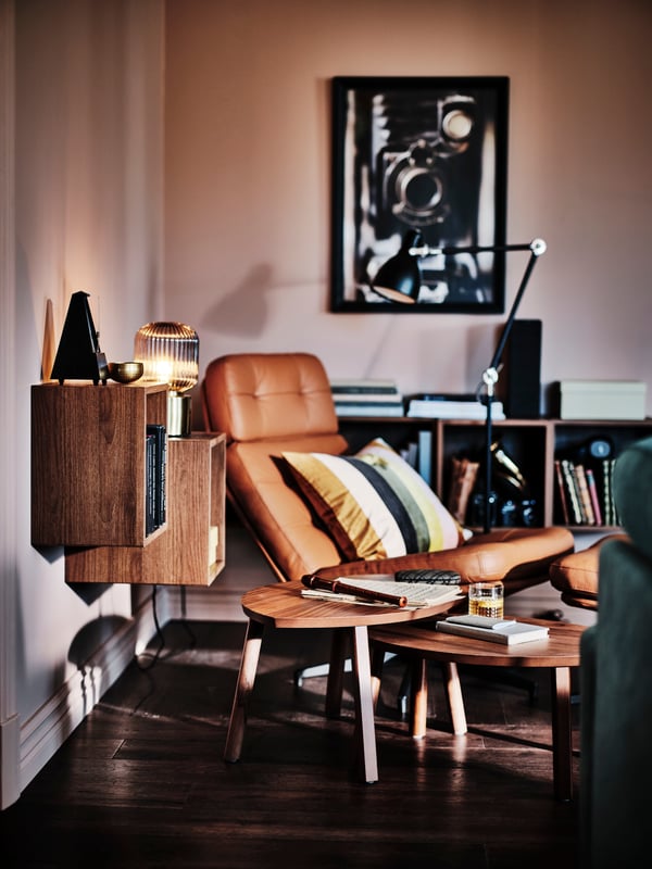 A HAVBERG armchair and footstool next to walnut veneer STOCKHOLM nest of tables, set of 2 below two EKET cabinets.