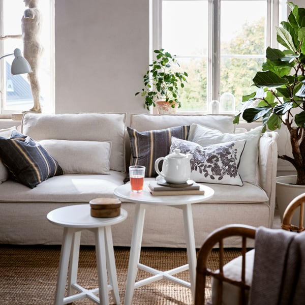 A SÖDERHAMN sofa in a living room, with different cushions lying on it, including a SKUGGNÄVA one with a floral pattern.