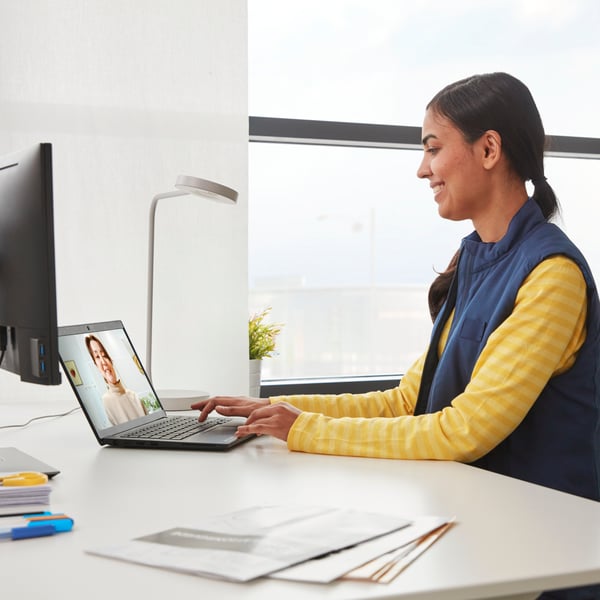 A woman smiling at a laptop with a customer on the screen