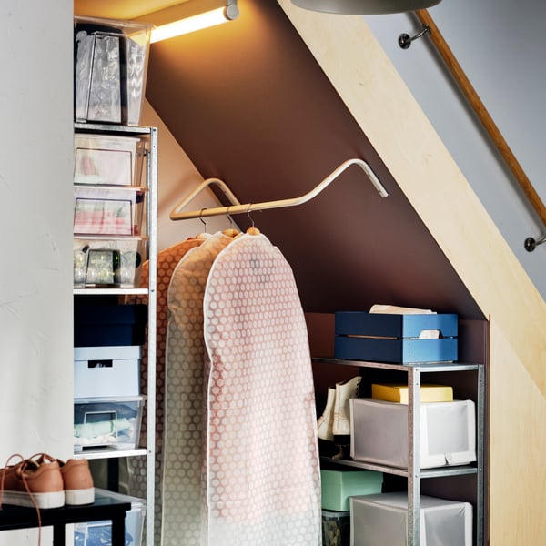 Clothes rack under staircase with well-organised shelving units, and boxes in different colours.