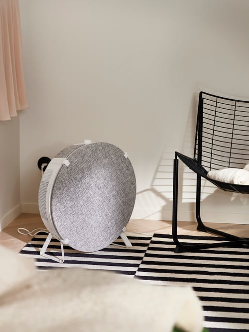 Bedroom featuring a white STARKVIND air purifier with integrated handle placed next to a black SKÅLBODA armchair.
