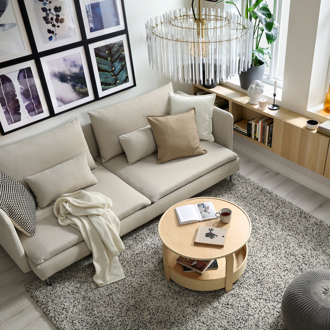 A modern living room with a light beige SÖDERHAMN sofa, cushions and a blanket.