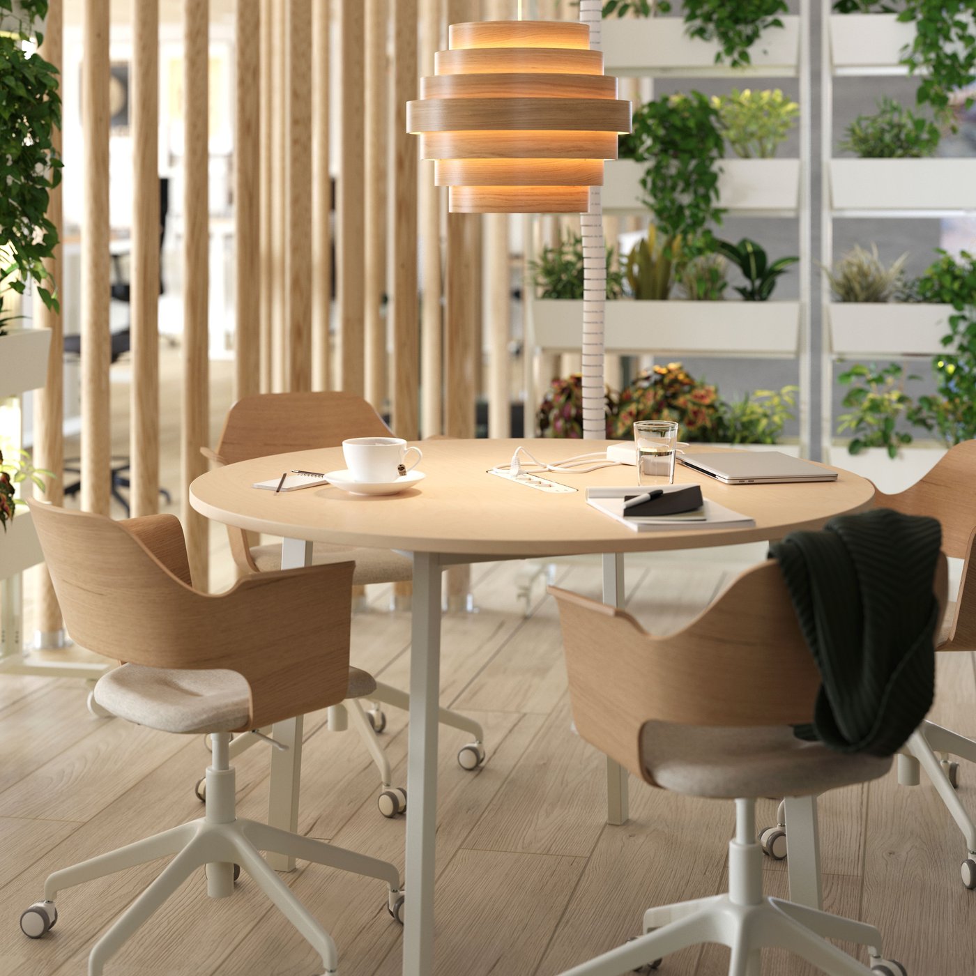 A DYKARKLOCKA pendant lamp shade with white stained oak veneer rings hangs over a round MITTZON conference table and chairs.
