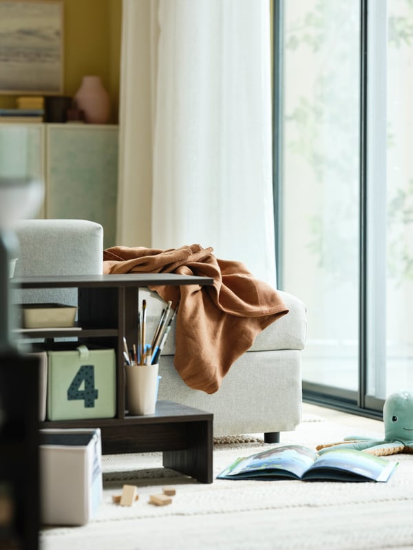 A beige VIMLE chaise longue with a light brown throw on it is facing a a large sliding door with white DYTÅG curtains.