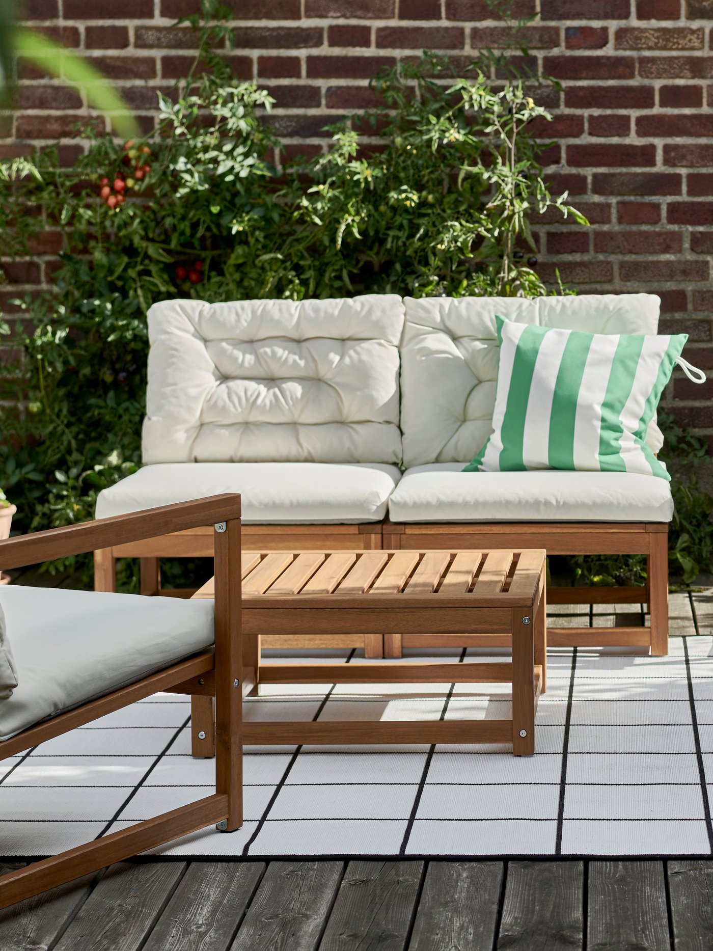 A NÄMMARÖ easy chair and a NÄMMARÖ sofa, with seat and back cushions, stand on a terrace on a sunny day.