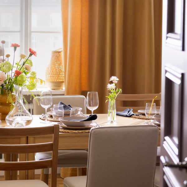 A TONSTAD table in oak veneer and TONSTAD chairs, the table set with glasses and tableware for a festive occasion.