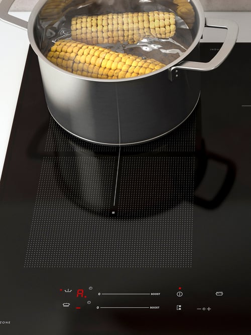 A stainless steel pot boiling two corn cobs on an induction hob, showing the auto-cook function.