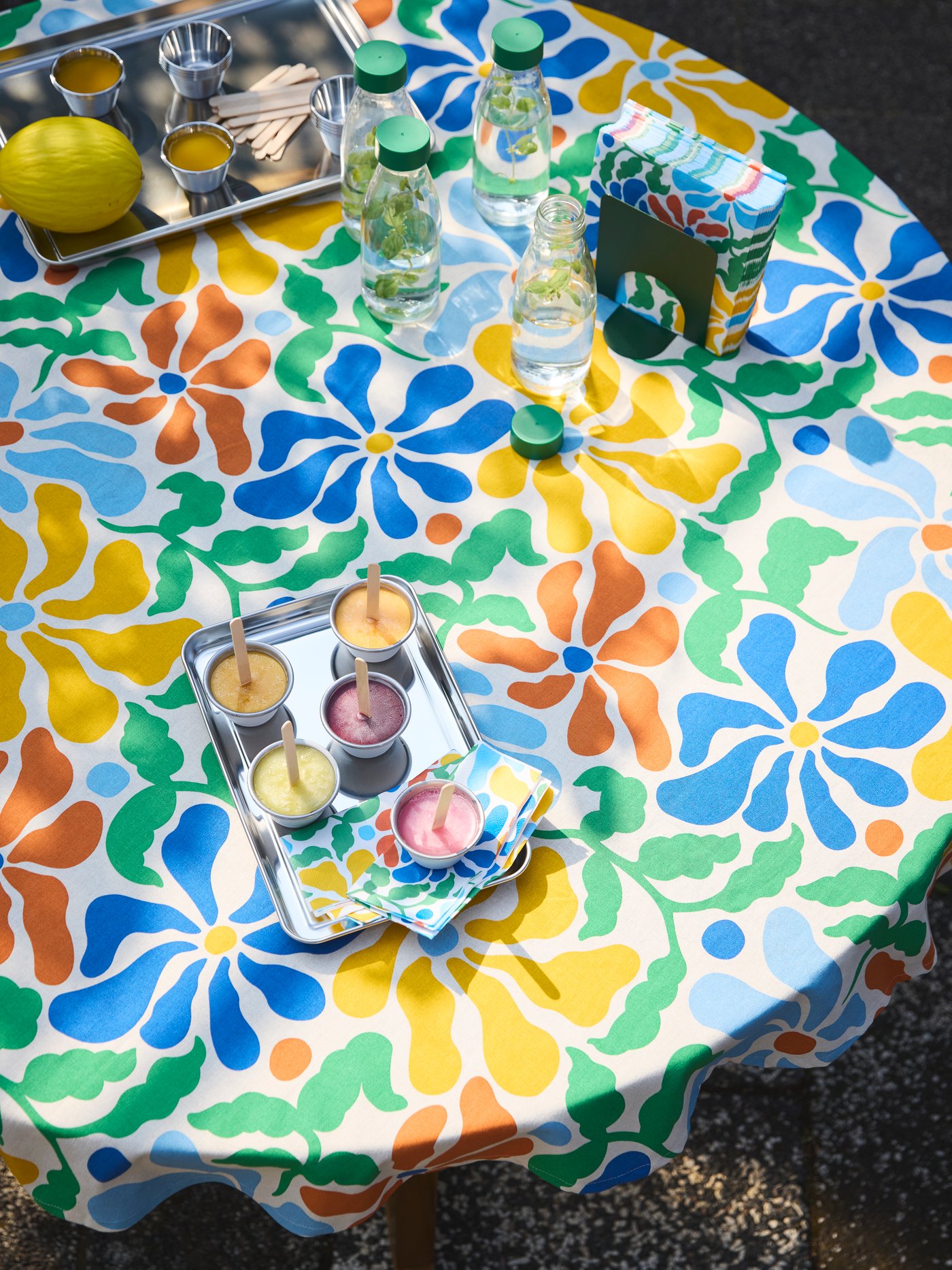 A table is set with PILLERSTARR tablecloth and napkins with a colorful floral pattern and homemade ice cream served on a tray.