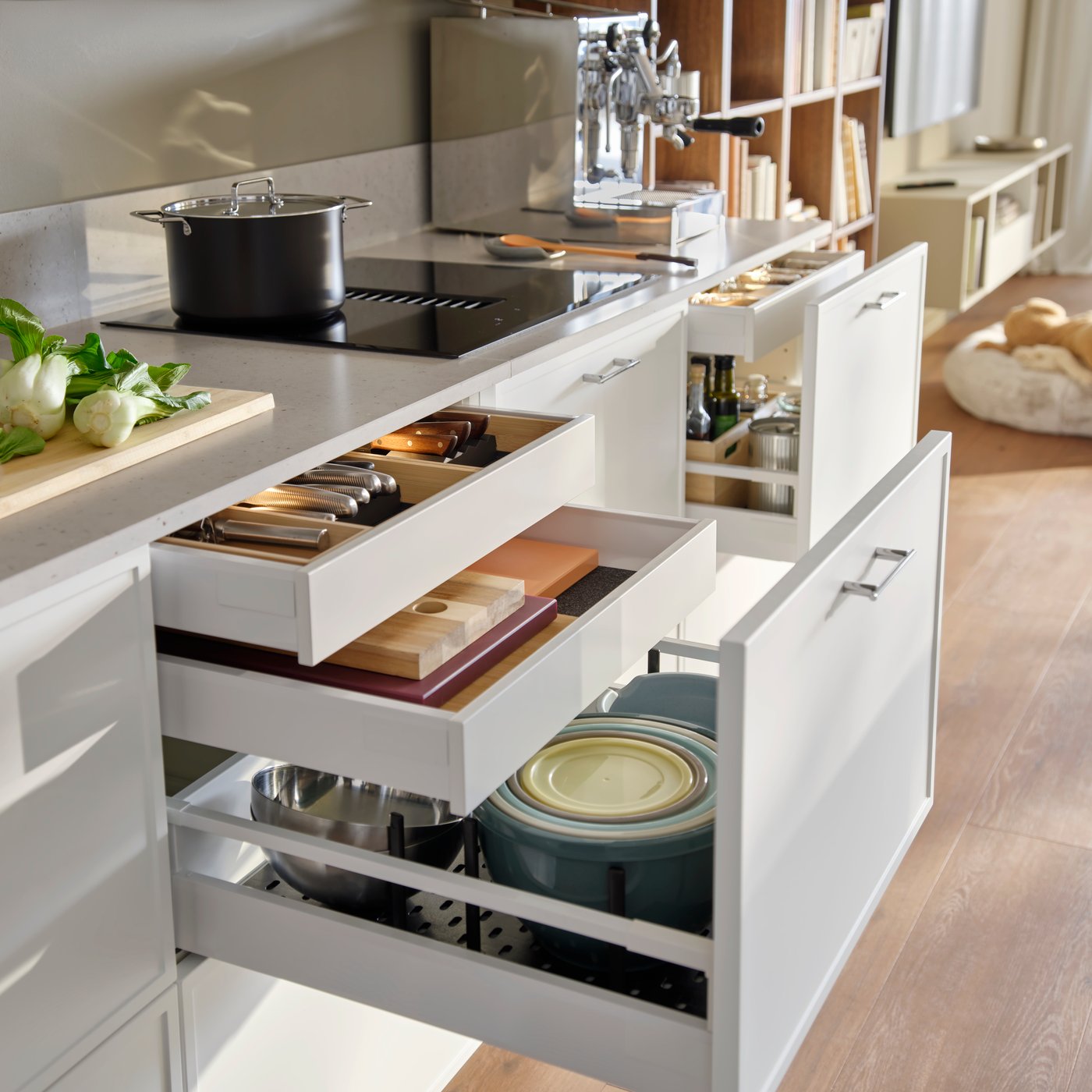 A kitchen with white METOD base cabinets features multiple drawers and with cookware displayed and utensils organised.