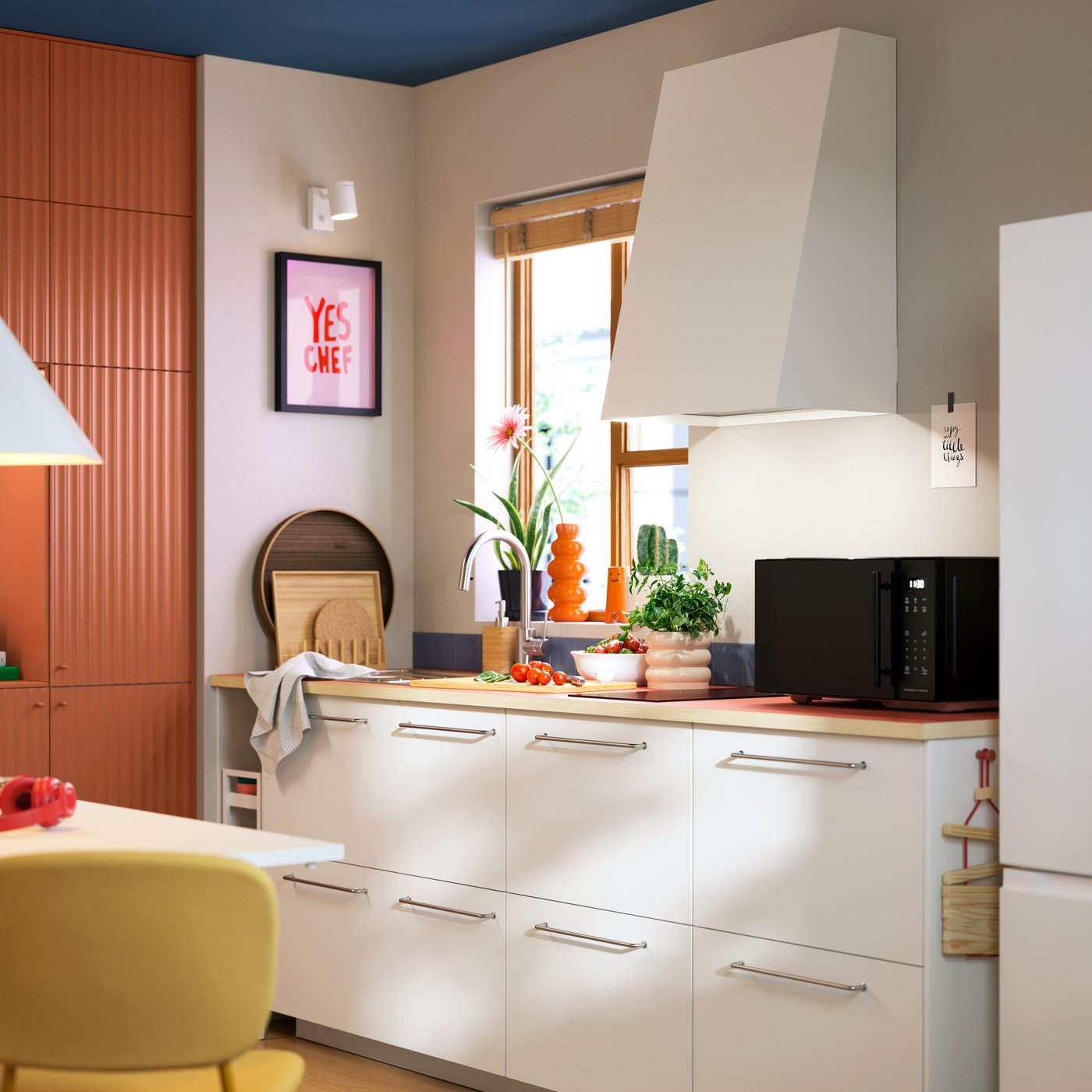 A small kitchen has base cabinets with white VALLSTENA fronts, a sink, a microwave oven and an extractor hood.