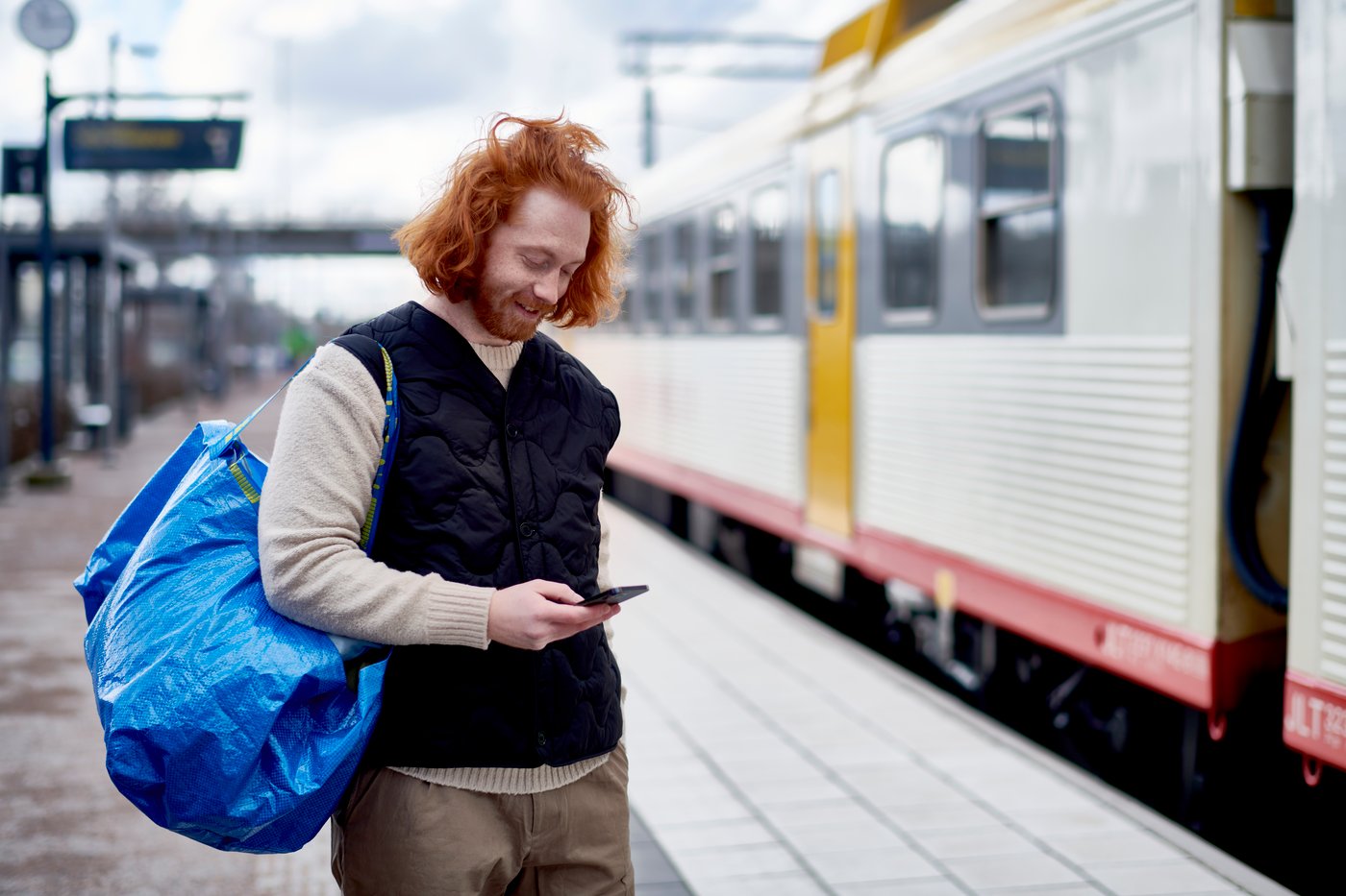 Mężczyzna uśmiechający się do telefonu na peronie