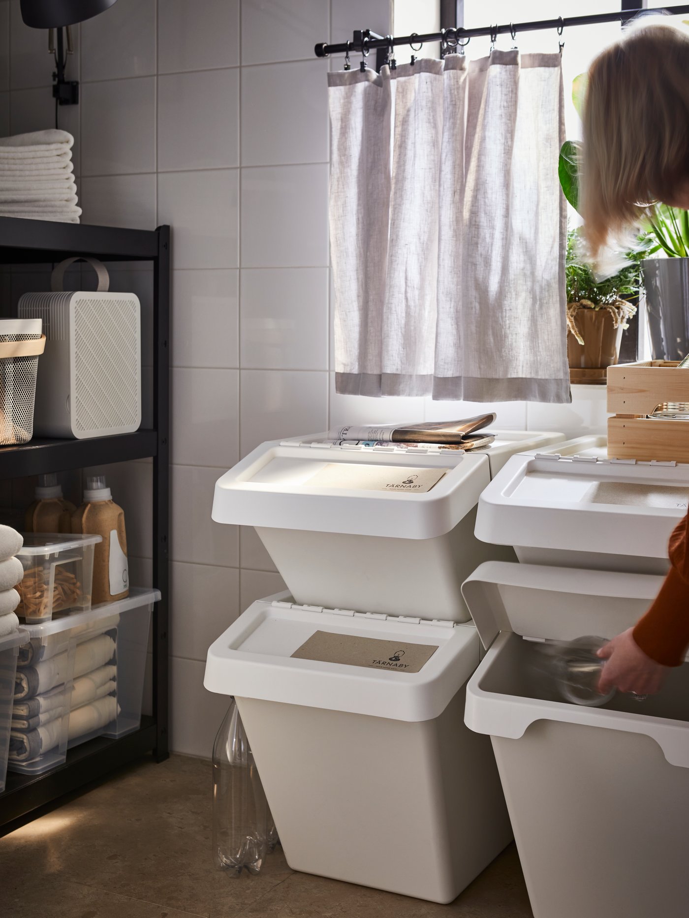 A collection of white trash bins sit stacked in a kitchen.