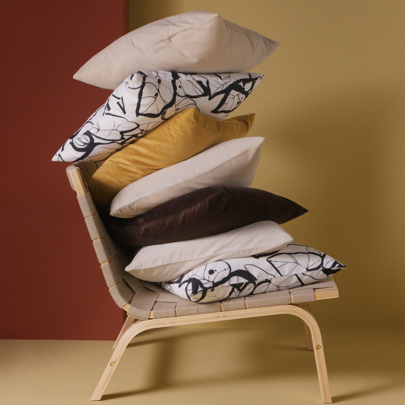 A wooden armchair with a stack of different cushions in various colours and patterns.
