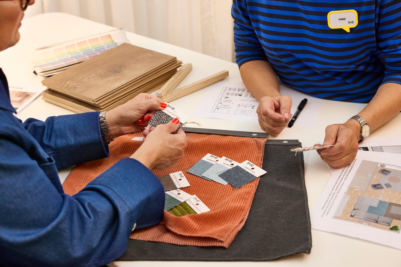 Pertsona bat ari da IKEA denda batean langile batekin oihal-laginak ikusten.