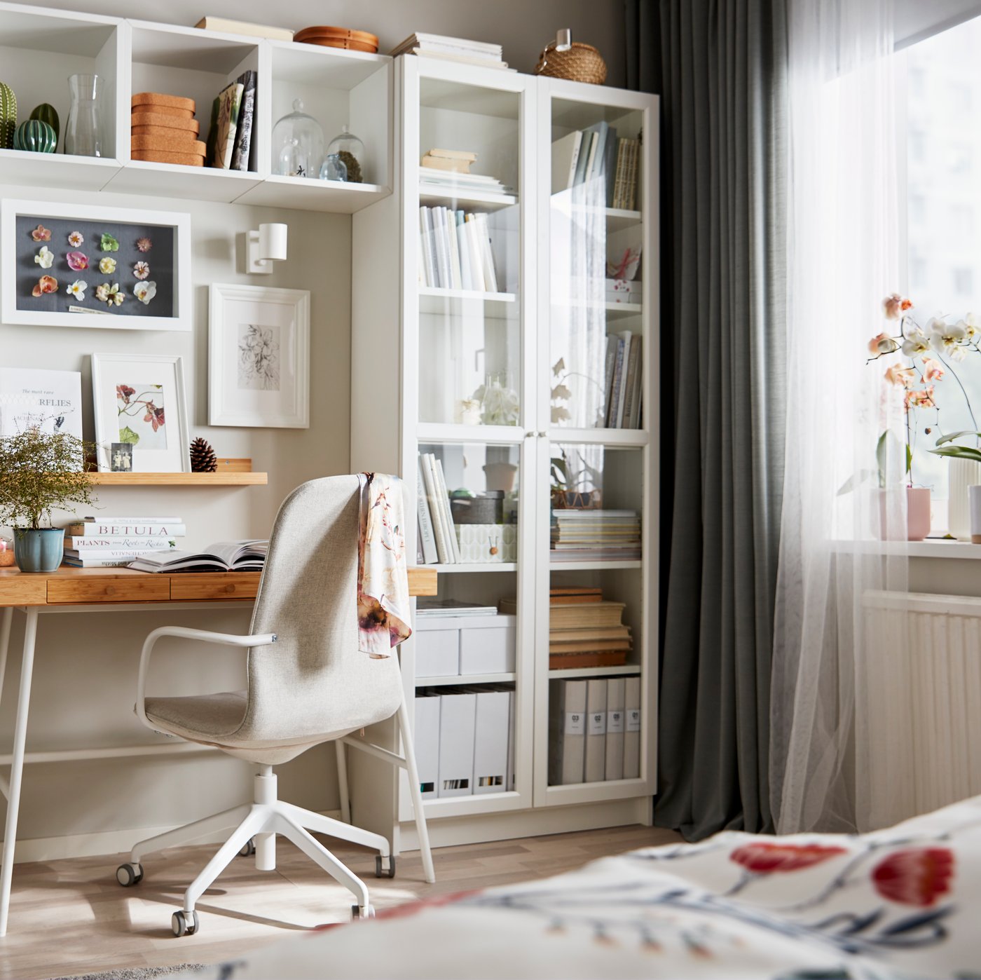 Un estante BILLY con puertas de cidrio y adentro del estante libros y carpetas.