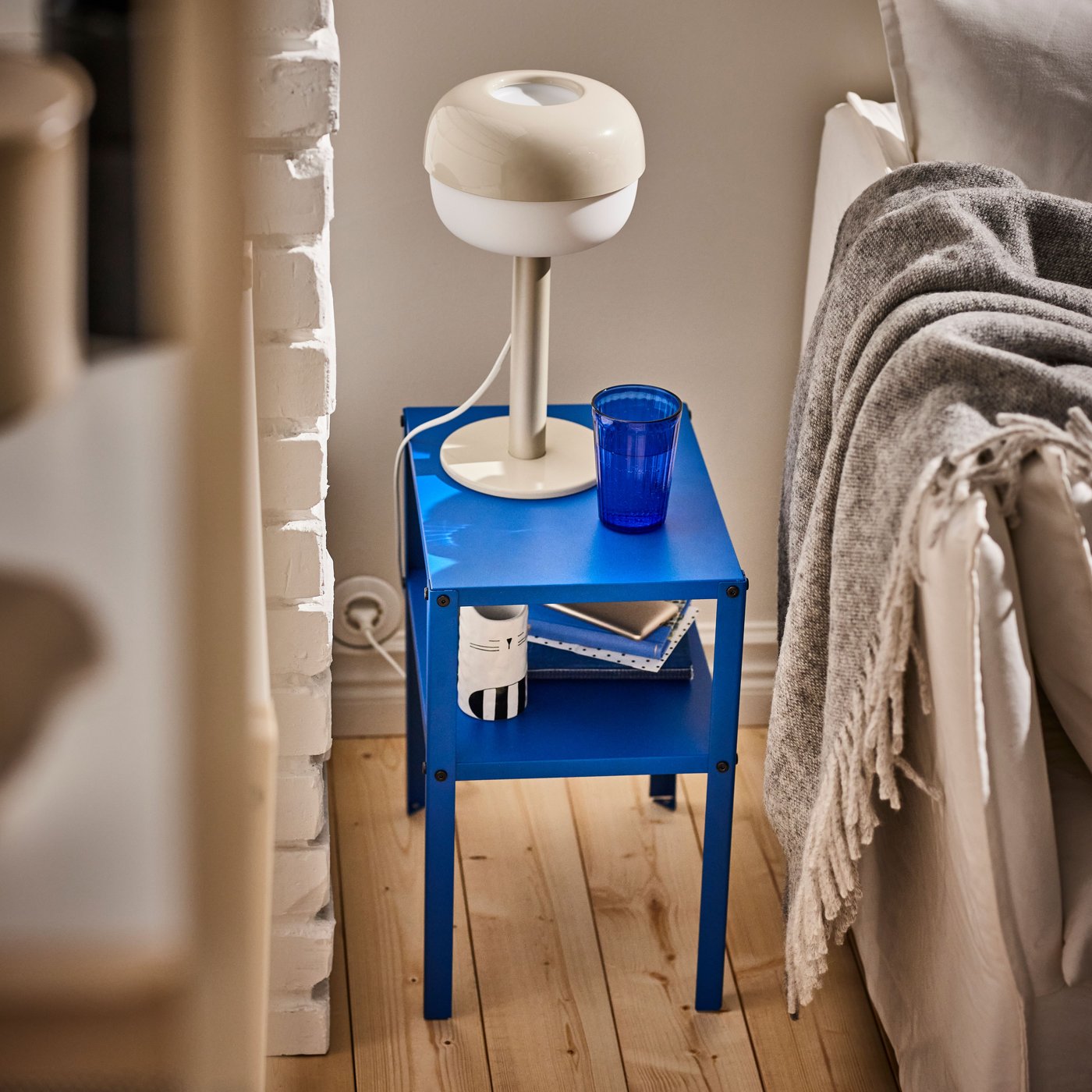 niebieski stolik nocny KNARREVIK stojący przy łóżku