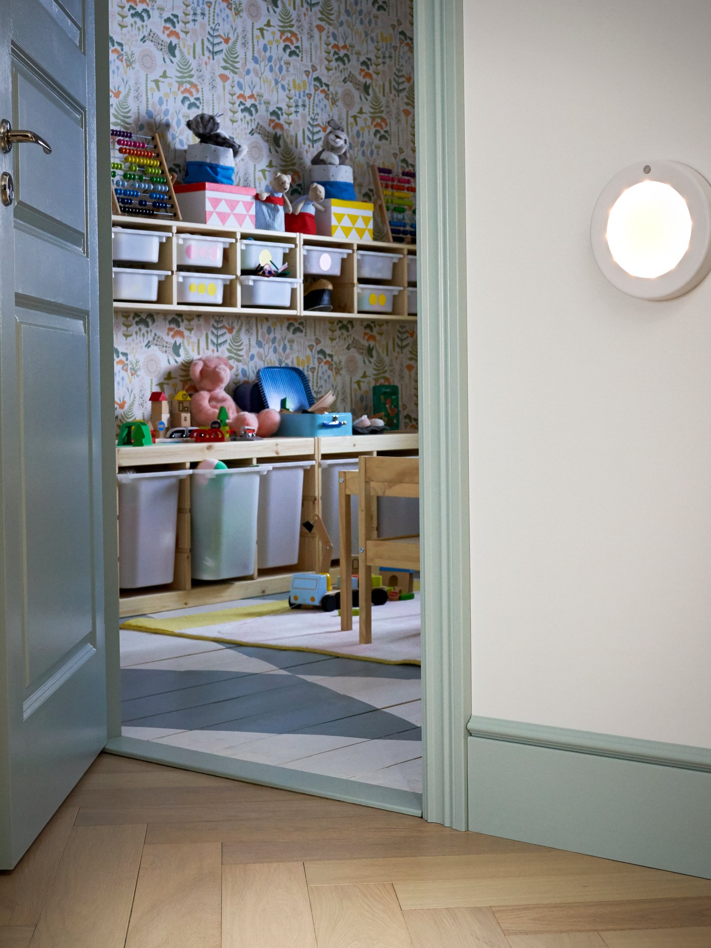 Een wit STÖTTA LED plafond-/wandlampje op batterijen met bewegingssensor in de hal/gang voor de kinderkamer.