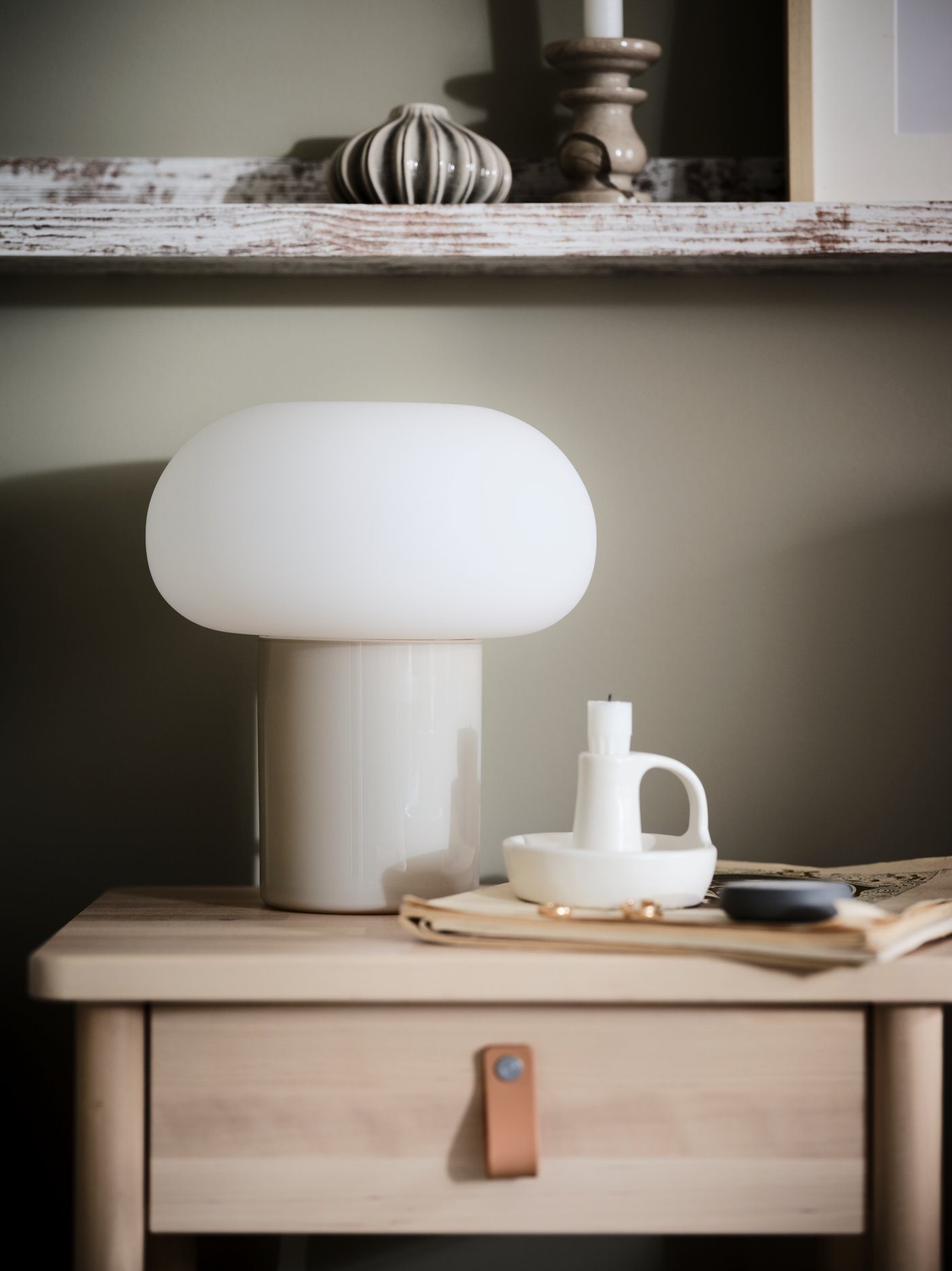 Koivuisen BJÖRKSNÄS-sivupöydän päällä on DEJSA-pöytävalaisin sekä valkoinen GODTAGBAR-kynttilänjalka.