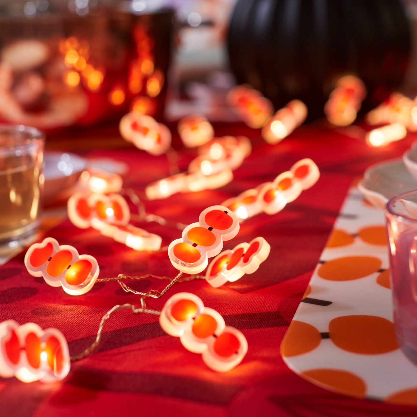 A table dressed with a red tablecloth and some lights decorated FÖSSTA pomegranate design.