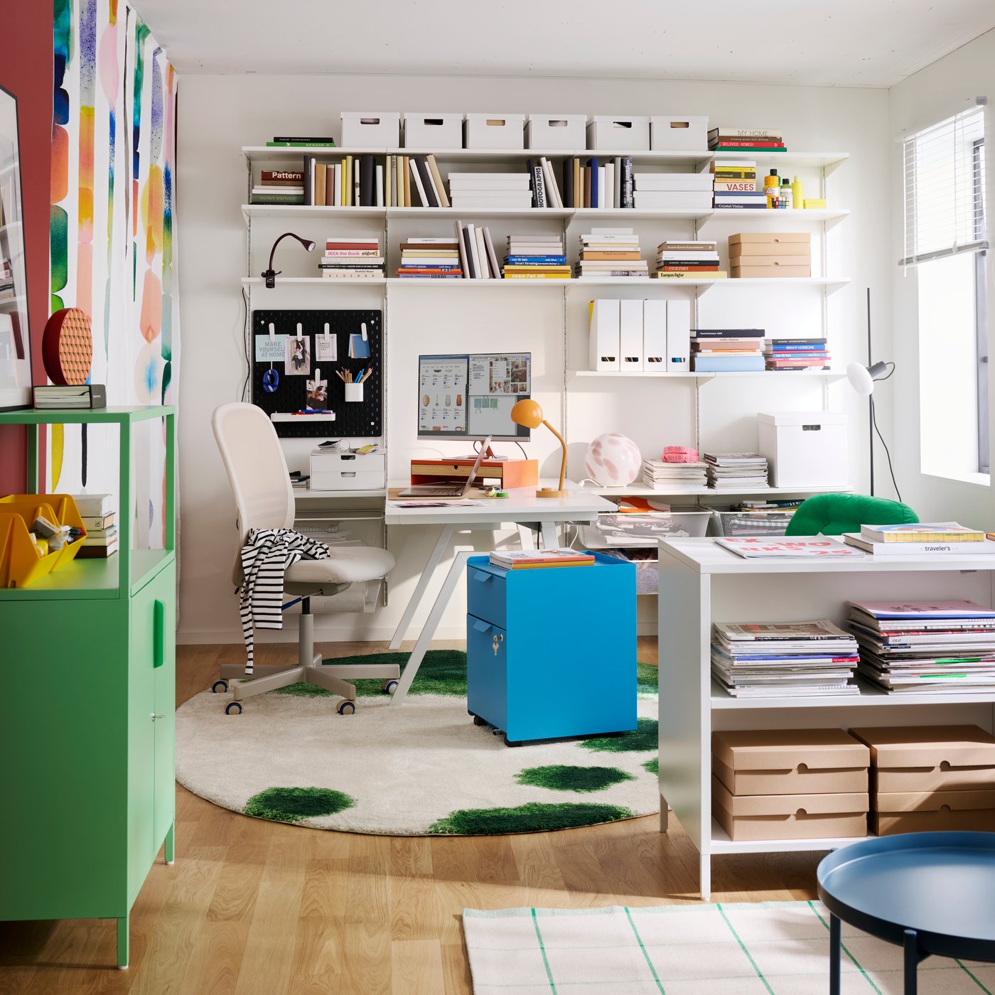 A home office features a blue TROTTEN drawer unit on castors, surrounded by shelves and a desk with stationery.