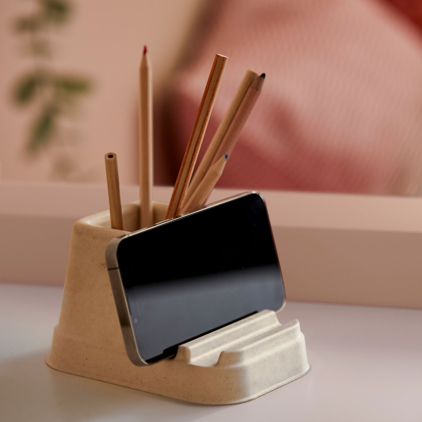 A HÖNSNÄT holder for mobile phone holding a horizontally placed mobile phone and several coloured pencils.