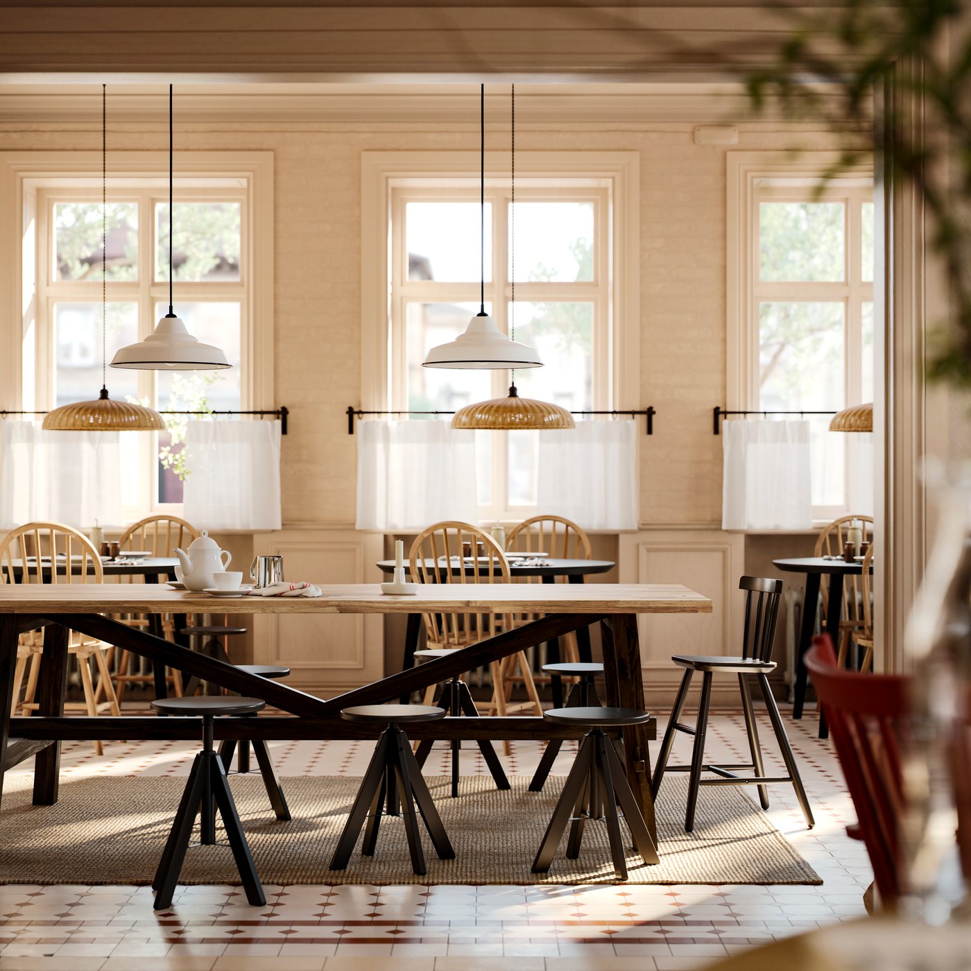 Una mesa de comedor SKOGSTA de acacia con patas negras tiene taburetes negros de altura ajustable alrededor de ella en un comedor comercial.