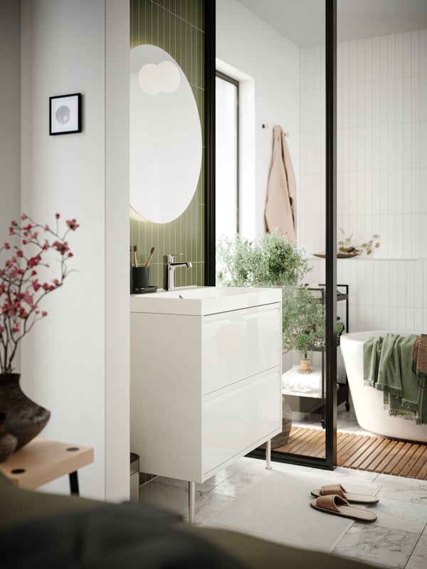 A bathroom featuring an ÄNGSJÖN wash-stand with drawer in high-gloss white, a BACKSJÖN wash-basin and a black mixer tap.