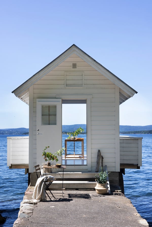 Liten vit sommarstug precis vid havet med brygga, 