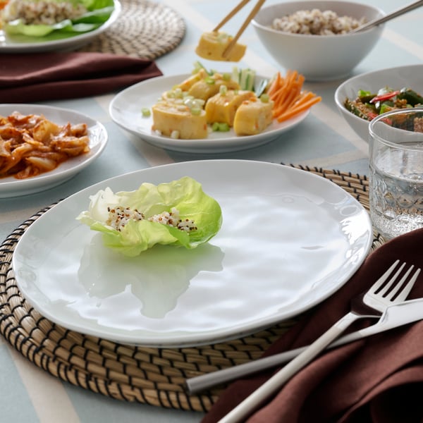 テーブルのホワイトのFORELLTETRA/フォレルテトラ プレートにレタスが1枚のっている。サイドプレートやボウルにも料理が盛りつけてある。