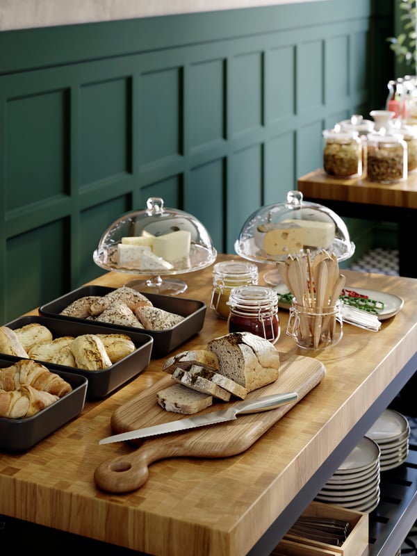 KORKEN jars with lid, an ARTISTISK chopping board and LYCKAD oven/serving dishes on a VADHOLMA kitchen island in a café.