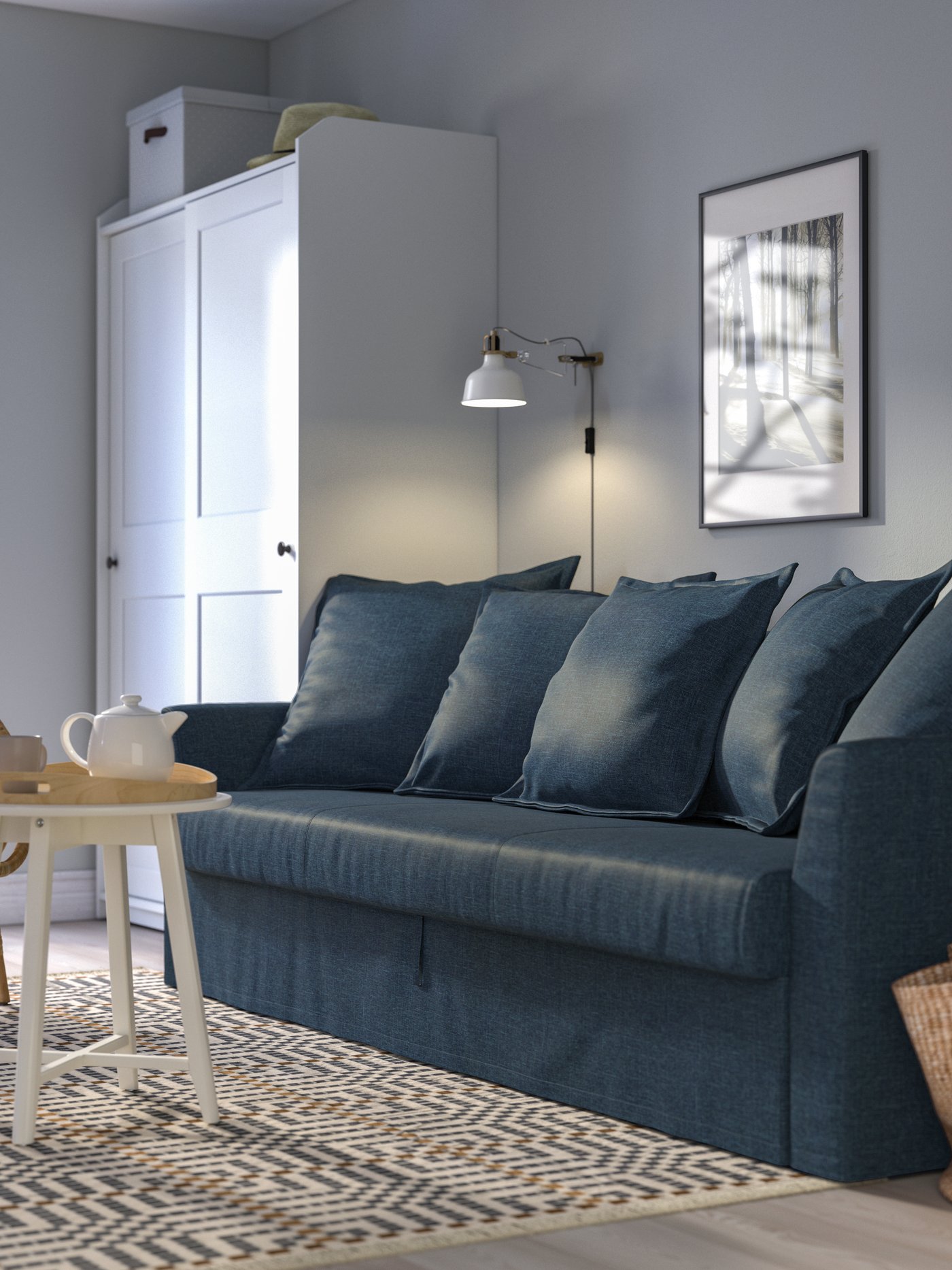 Mörkblå HOLMSUND bäddsoffa placerad i ett luftigt vardagsrum.