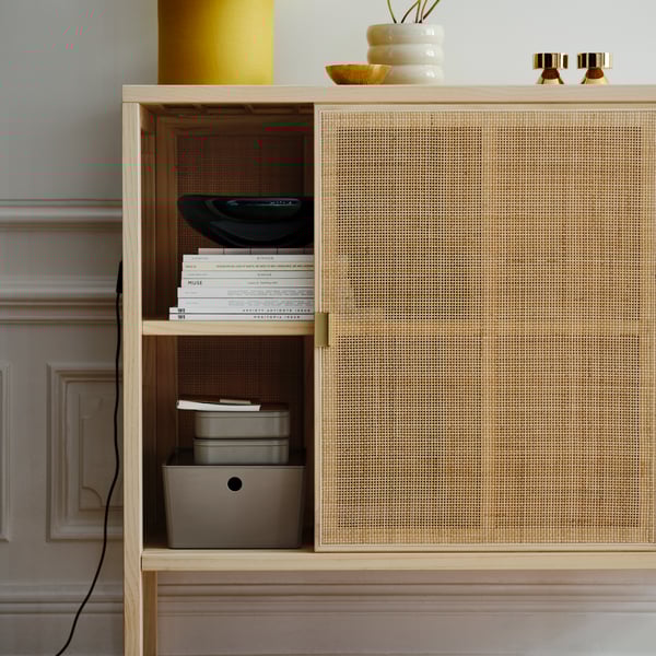 Harmaanbeige HARVMATTA-säilytyslaatikko rottinkisen IKEA STOCKHOLM 2025- kaapin sisällä.